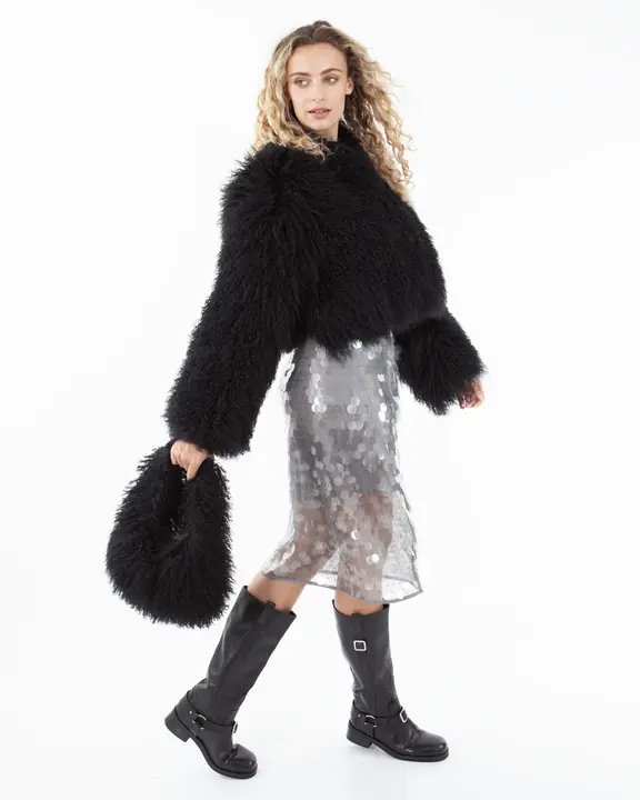 Editorial fashion pose in a black shearling jacket and silver skirt
