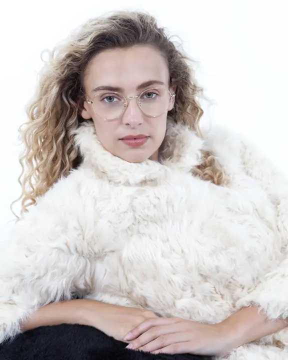 Model portfolio headshot with gold glasses and a cream shearling coat