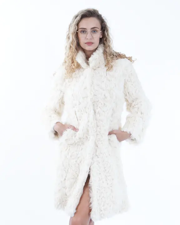 Three-quarter model portrait in a cream shearling coat and glasses